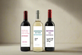 Three wine bottles with humorous labels on a light gray background