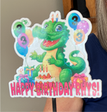 a happy green alligator with balloons, cake and presents