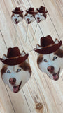 Husky dog faces with cowboy hats on a wooden surface