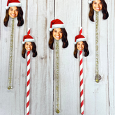 red and gold straws and stir sticks with a woman wearing a santa hat