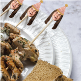 Skewers with food on a plate with decorative face sticks.