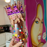 Decorative wine glass with figurines and colorful base, held in a kitchen.