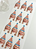 a womens face cut out wearing a blue striped pink and yellow party hat on a sheet of custom stickers