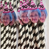 An old lady wearing a striped pink party hat with the number 90 on black and white straws