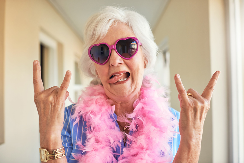 Rocking old lady wearing sunglasses and sticking her tongue out wearing a feather boa