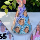 Decorative cone hat with cut-out faces and numbers on a white surface with greenery in the background