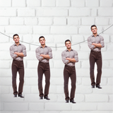 Four identical men standing against a white brick wall.