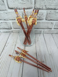 women's face wearing a party hat on rose gold straws in a cup with a light grey brick background