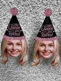 blond womans face with a black and pink party hat strung on a banner