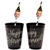 Two custom retirement party face straws with a photo of a man wearing a party hat and the text 'HAPPY RETIREMENT!' on black cups with glitter and star decorations.