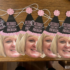 woman wearing a black and pink glitter party hat that reads "Retired Not My Problem"