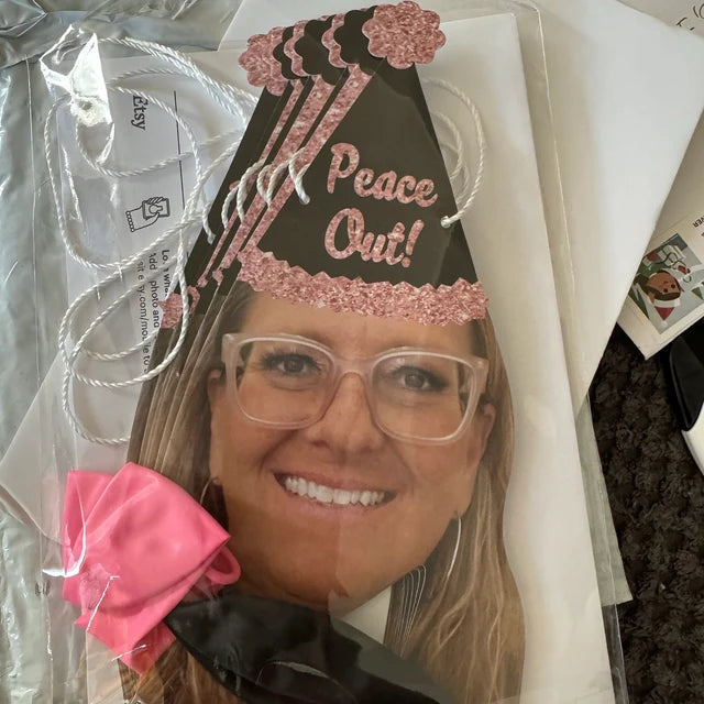 woman wearing glasses and wearing a party hat that reads "Peace Out"