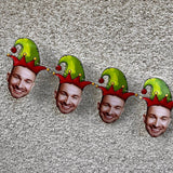 mans face cut out wearing a red and green elf hat strung on twine