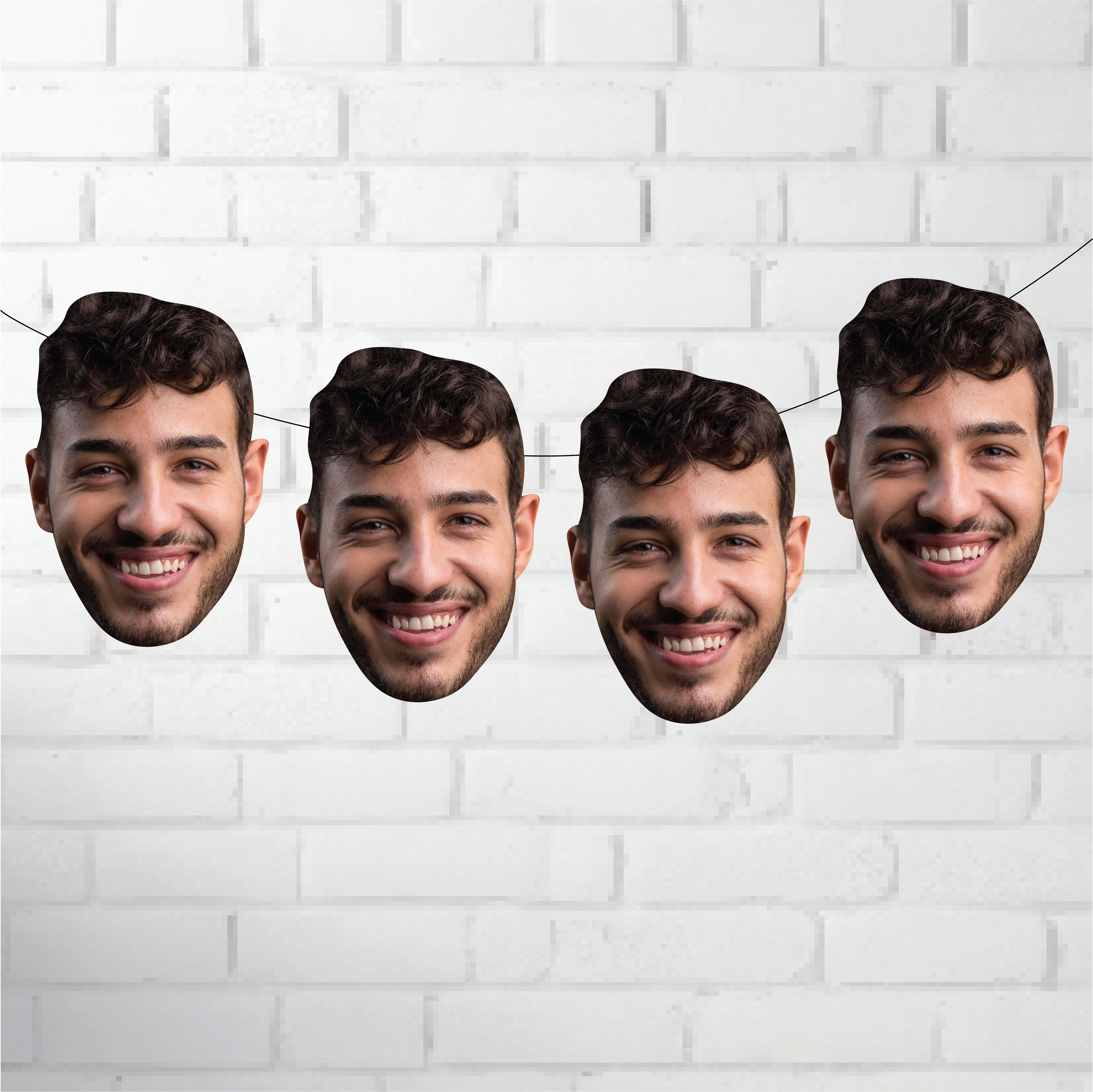 Four cardboard cutouts of a smiling man's face against a white brick wall background.