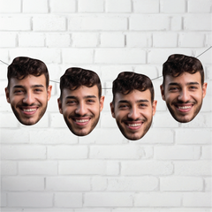Four cardboard cutouts of a smiling man's face against a white brick wall background.