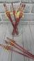 women's face wearing a party hat on rose gold straws in a cup with a light grey brick background