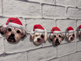 dogs wearing santa hats strung on twine against a white brick wall